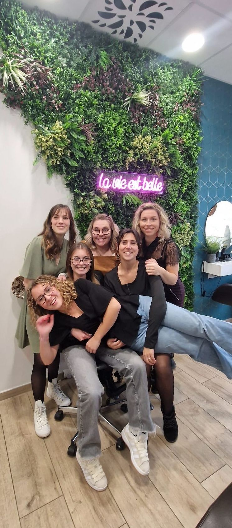 Un groupe de personnes pose pour une photo devant un mur végétal.
