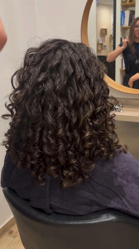 Une femme porte un chignon tressé avec une perle dedans.