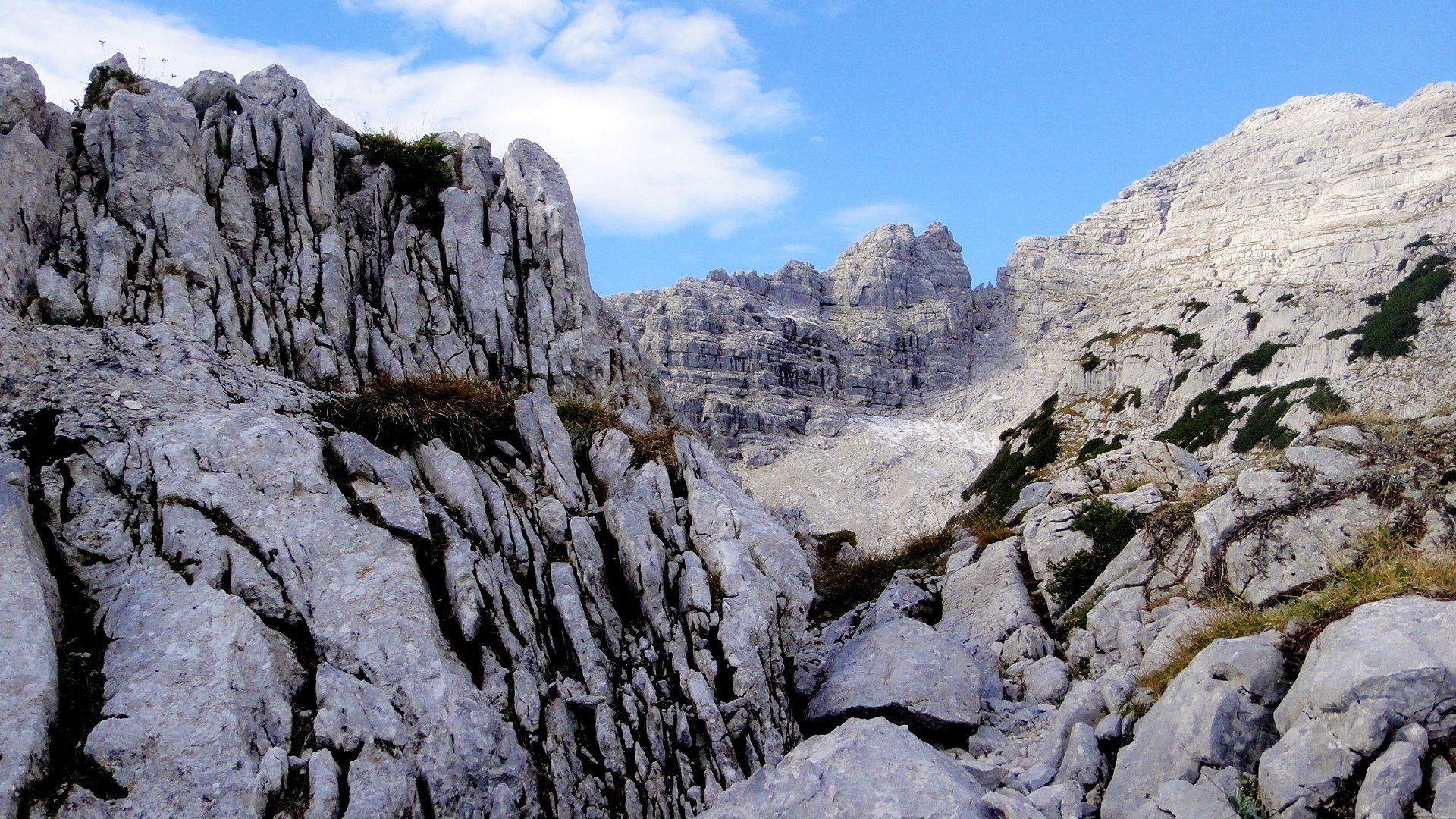 Felsige Berggipfel und eine enge Schlucht unter blauem Himmel.