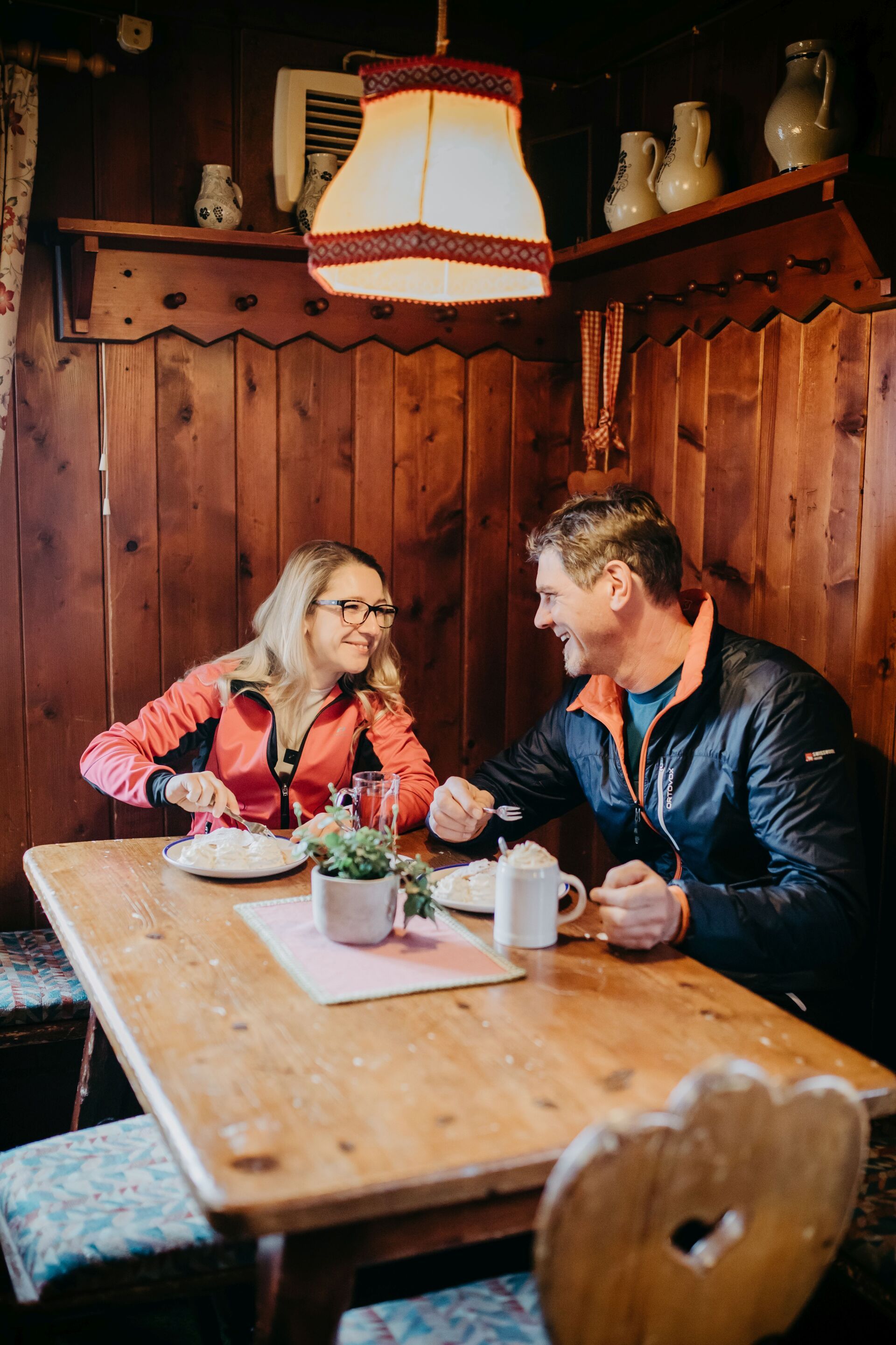 Ein lächelndes Paar isst an einem Holztisch in einer rustikalen Restaurantnische.