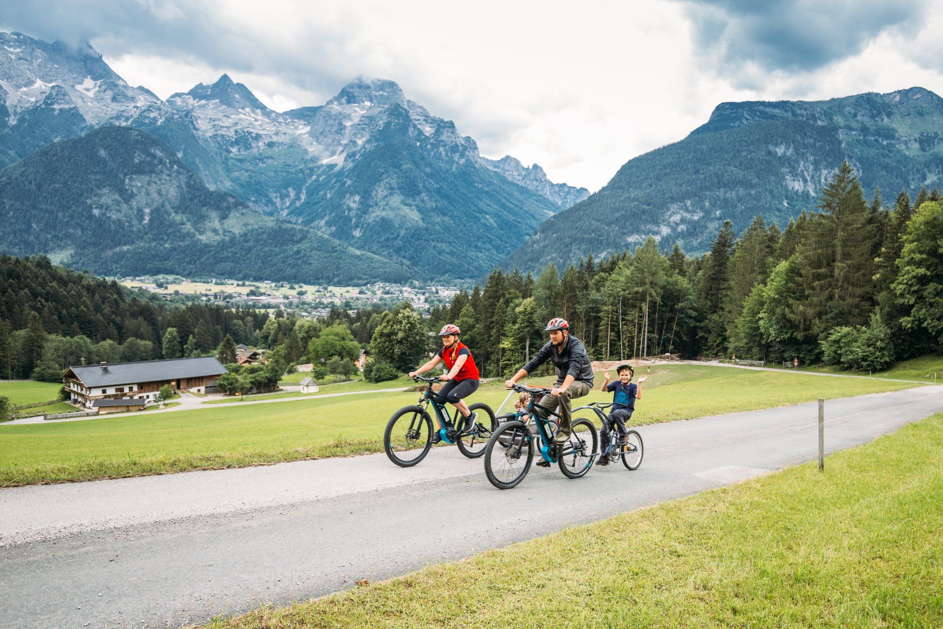 a group of people are riding bicycles down a road with mountains in the background