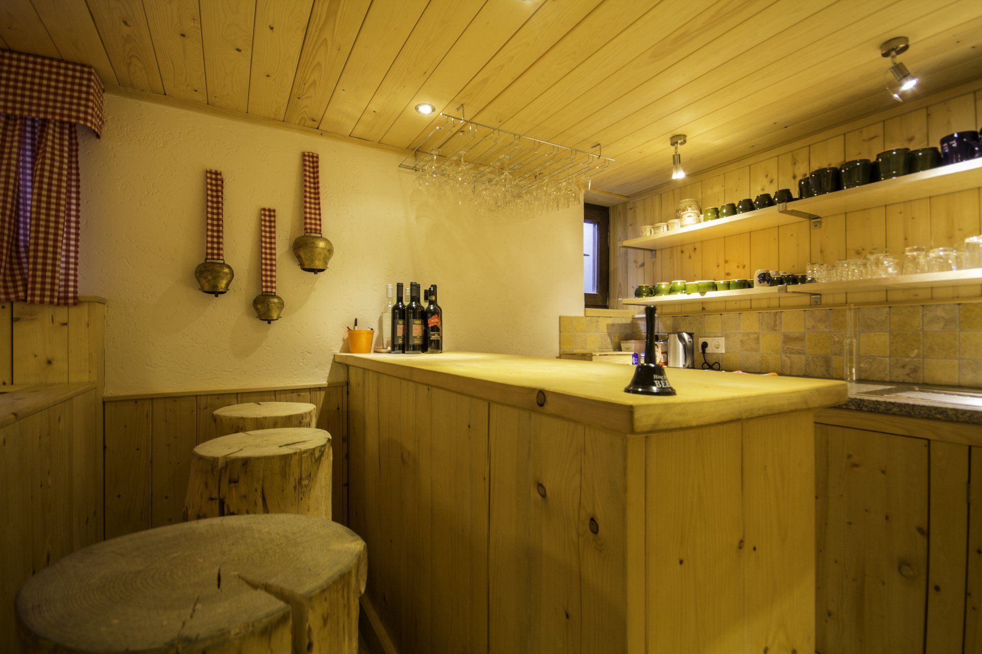 Rustikales Bar-Interieur mit Holzvertäfelung, Baumstumpfhockern und Flaschen in Regalen.