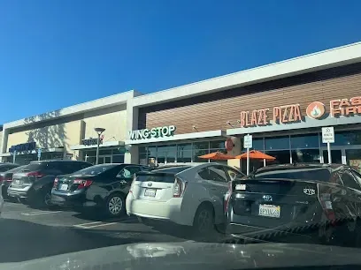 Tree Service Elmonte-Outdoor scene with a conical metallic sculpture on a grassy area in front of a modern, angular building. The sky is clear and sunny, creating a serene atmosphere.