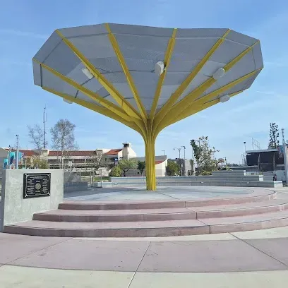 Tree Service El Monte Ca - A large, modern, yellow metal sculpture resembling an inverted umbrella stands over a circular platform. The sky is clear, creating a peaceful atmosphere.