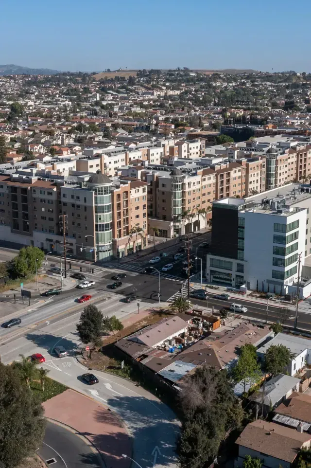 Tree Service El Monte Ca - Aerial view of a busy urban intersection with modern apartments, homes, and hills in the background under clear blue skies.