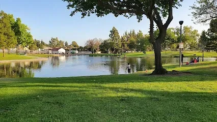 Tree Service El Monte Ca - Three-story historic building on a sunny street corner, featuring arched windows and a fire escape. Palm trees and blue sky create a serene urban scene.