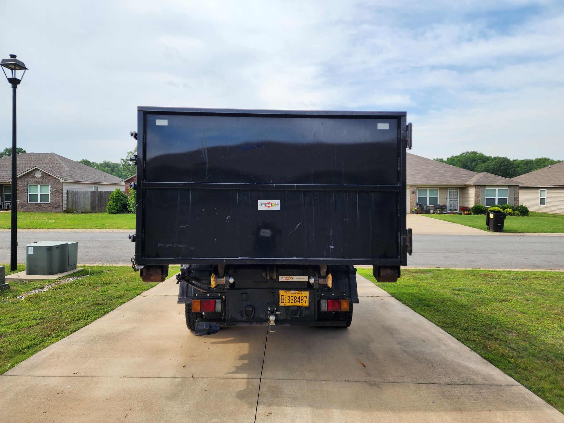 A dump truck is parked in a driveway in front of a house.