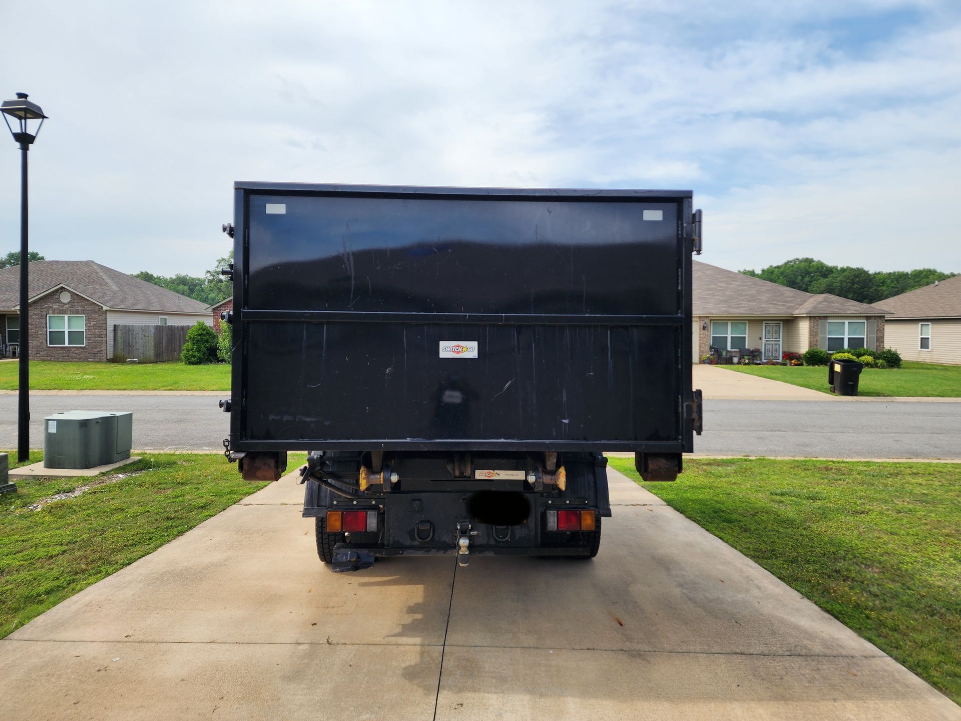 A dump truck is parked in a driveway in front of a house.