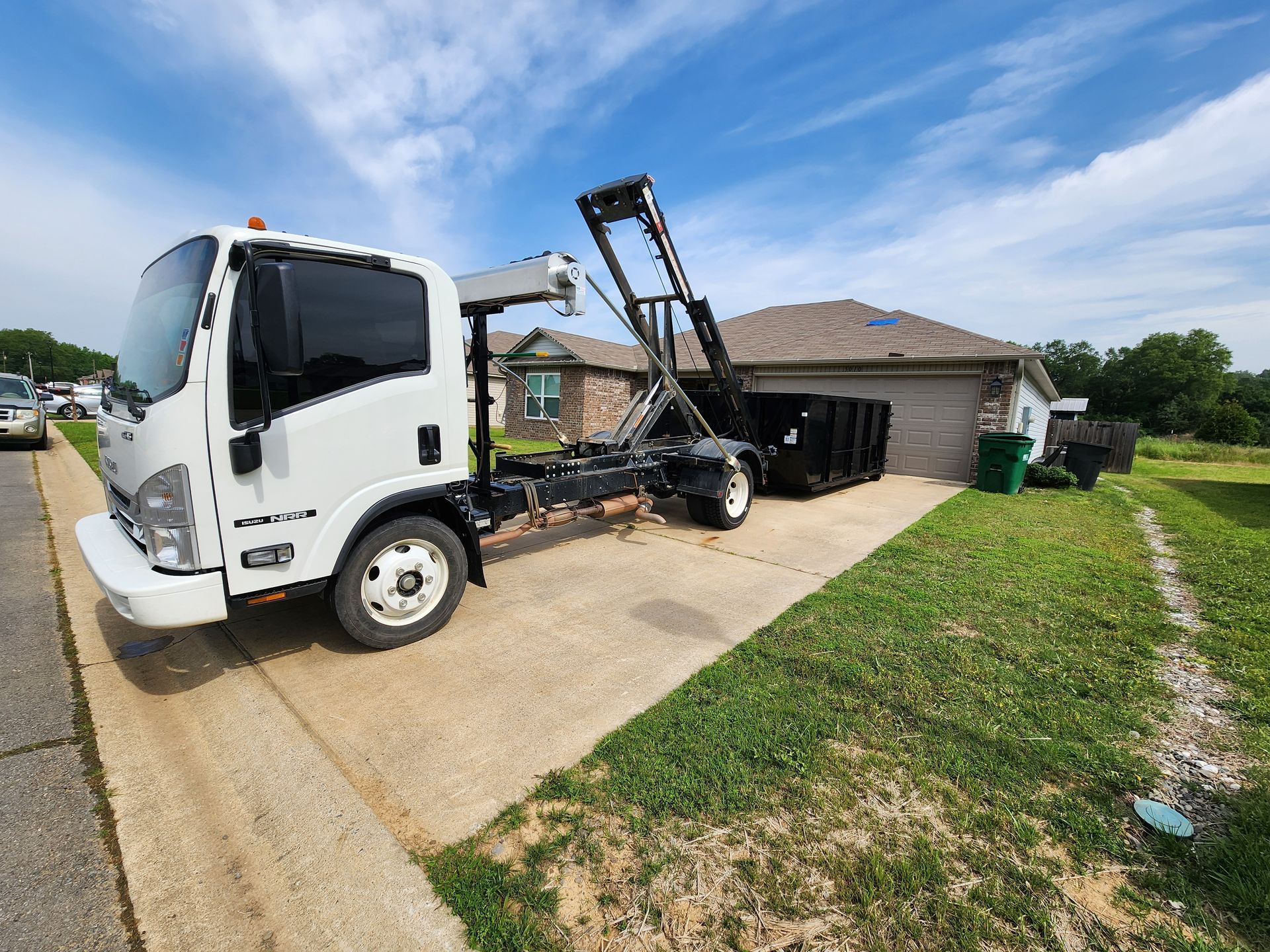 A white dump truck is parked in front of a house.