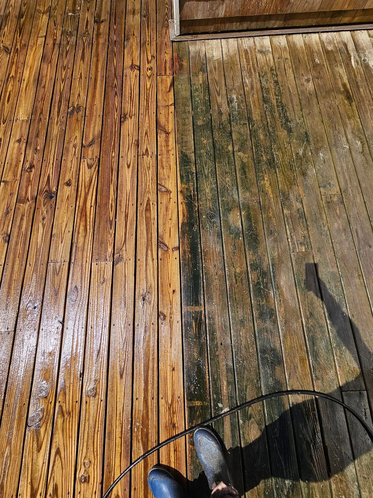 A pressure washer sprays a stream of water onto a dark, weathered wooden deck, cleaning it to reveal a lighter tone. A pressure washer sprays a stream of water onto a dark, weathered wooden deck, cleaning it to reveal a lighter tone.