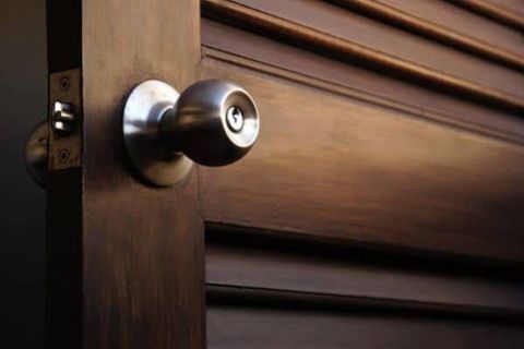 Silver door knob on a dark wooden louvered door