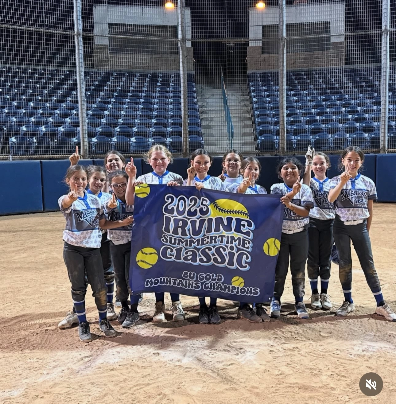 Youth softball team holding a banner, celebrating a tournament win, wearing team uniforms.