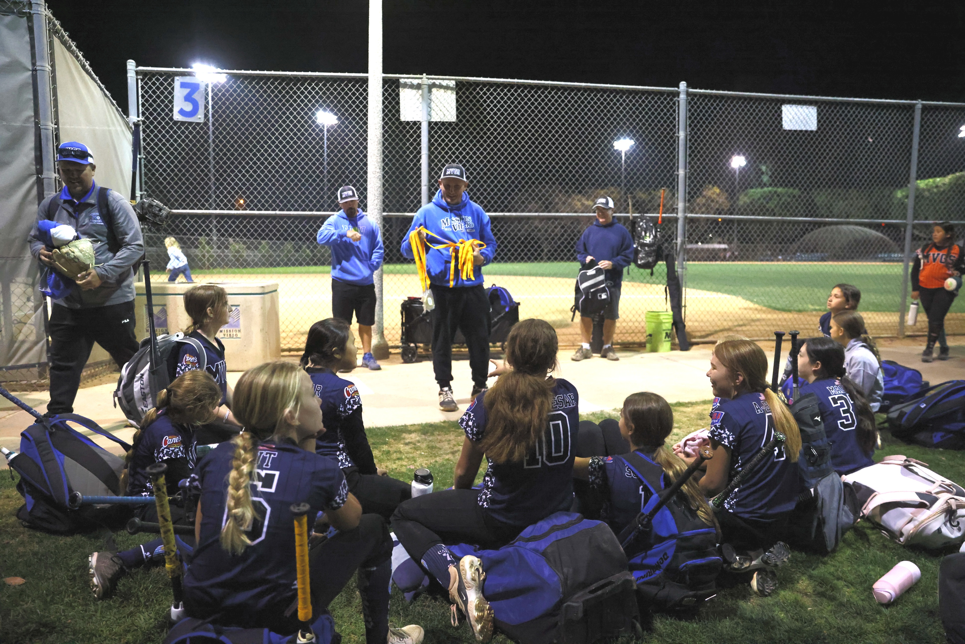 Softball team in blue and black uniforms walking on a field after a game.