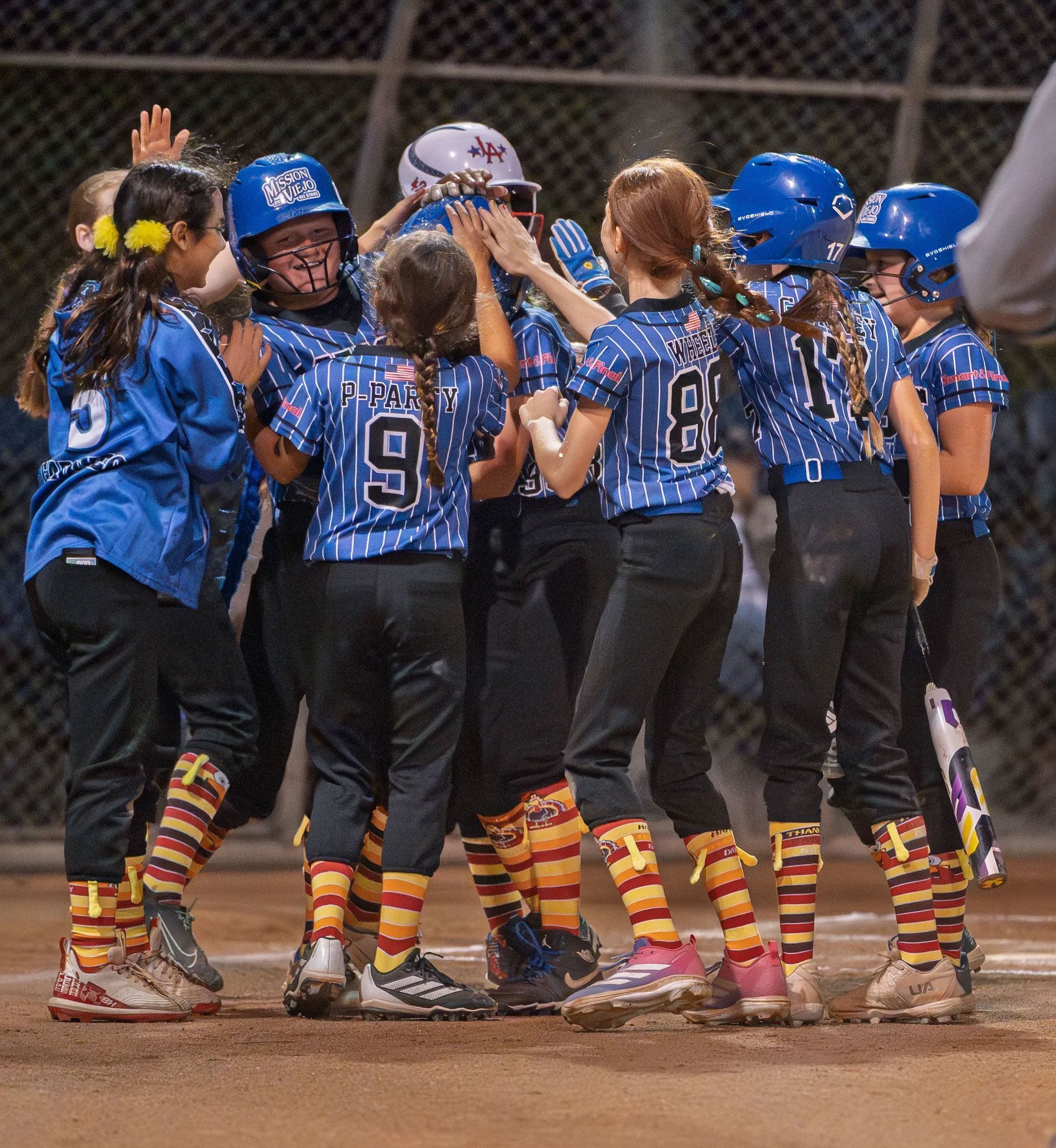 Softball team in blue and black uniforms walking on a field after a game.