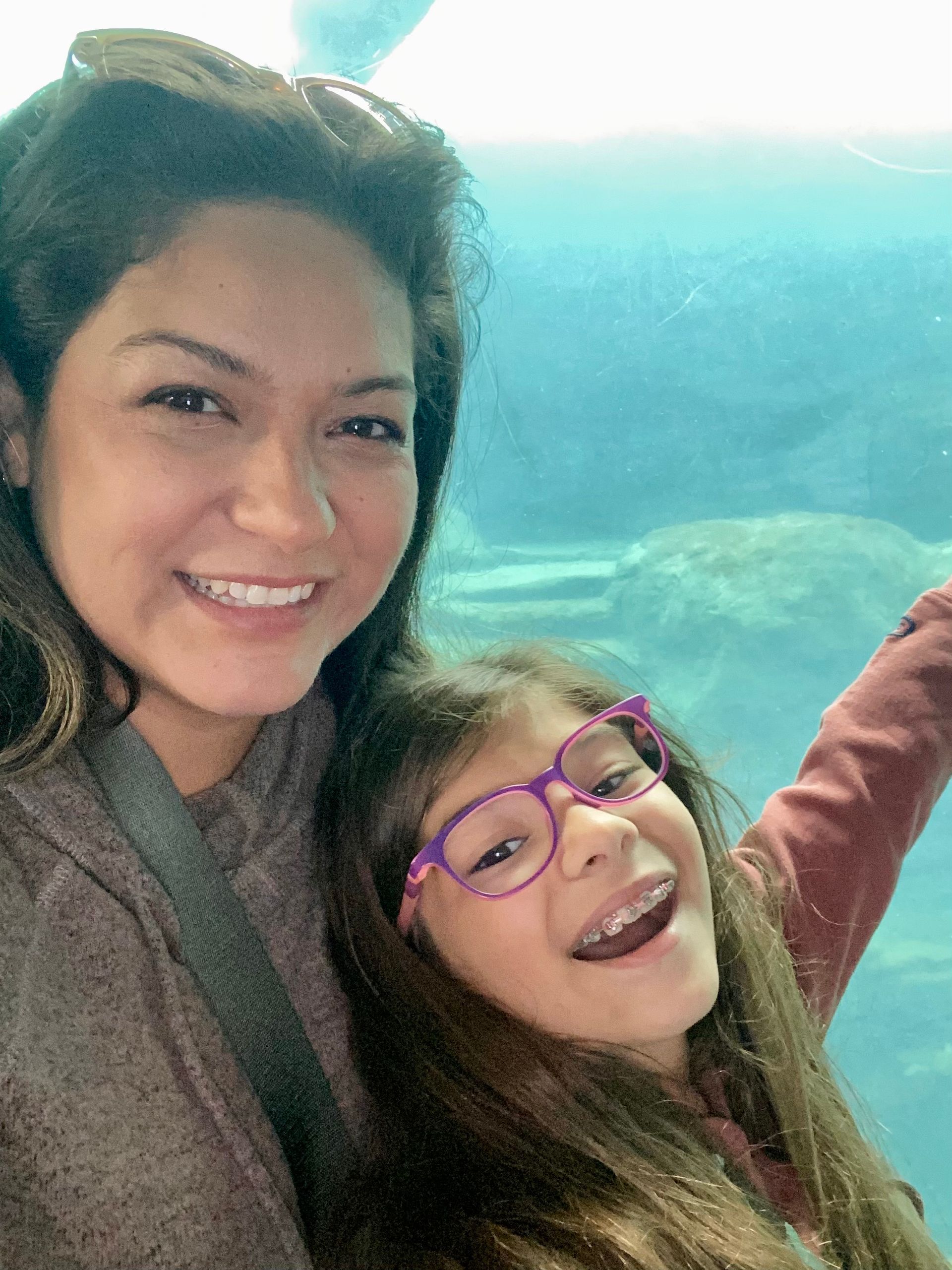 Woman and child smiling, looking at a sea turtle in an aquarium.