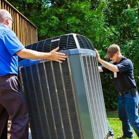 Astoria Heating & Cooling
technicians are carrying a large air conditioner outside.