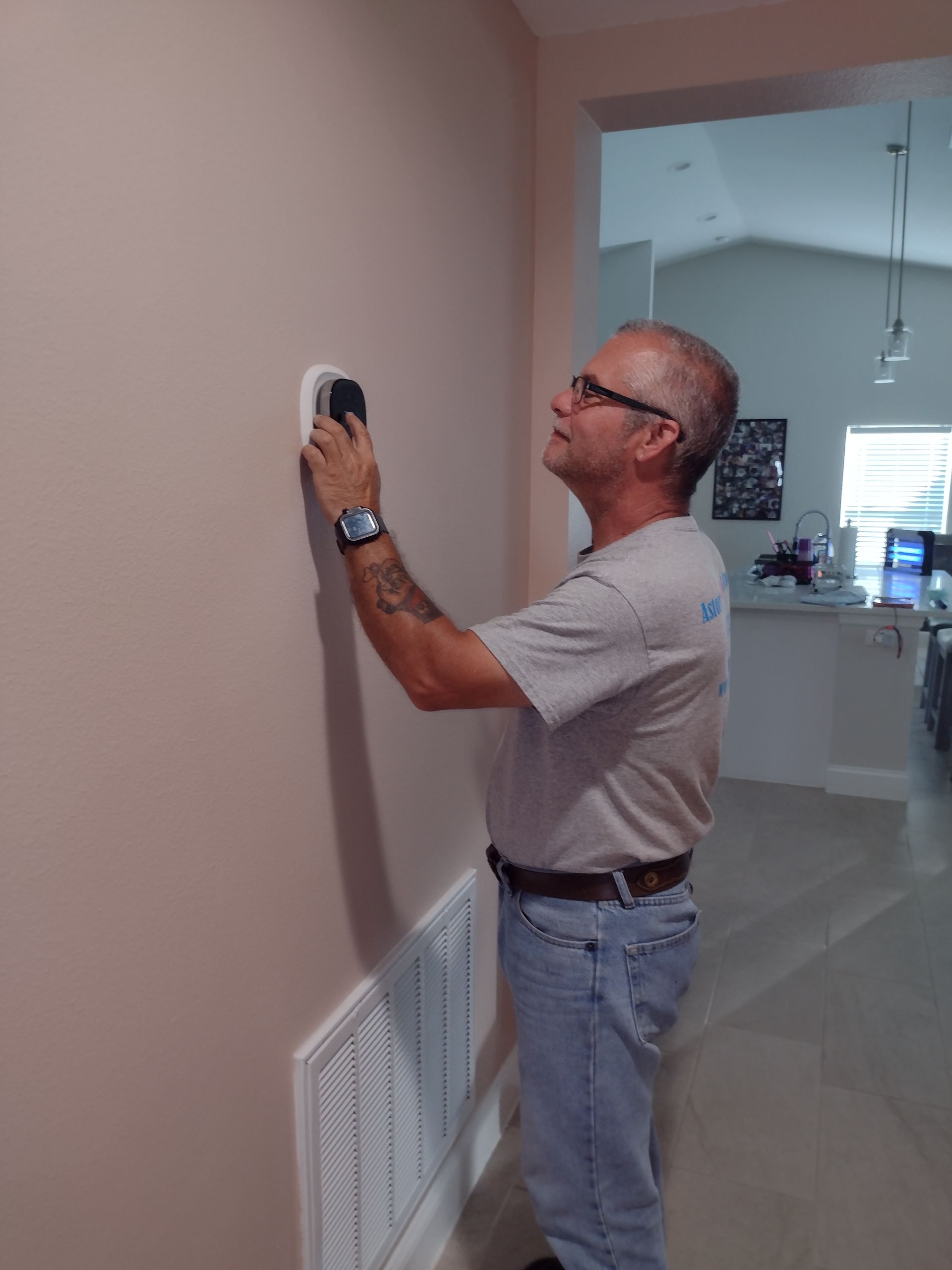 a man is adjusting a thermostat on a wall .