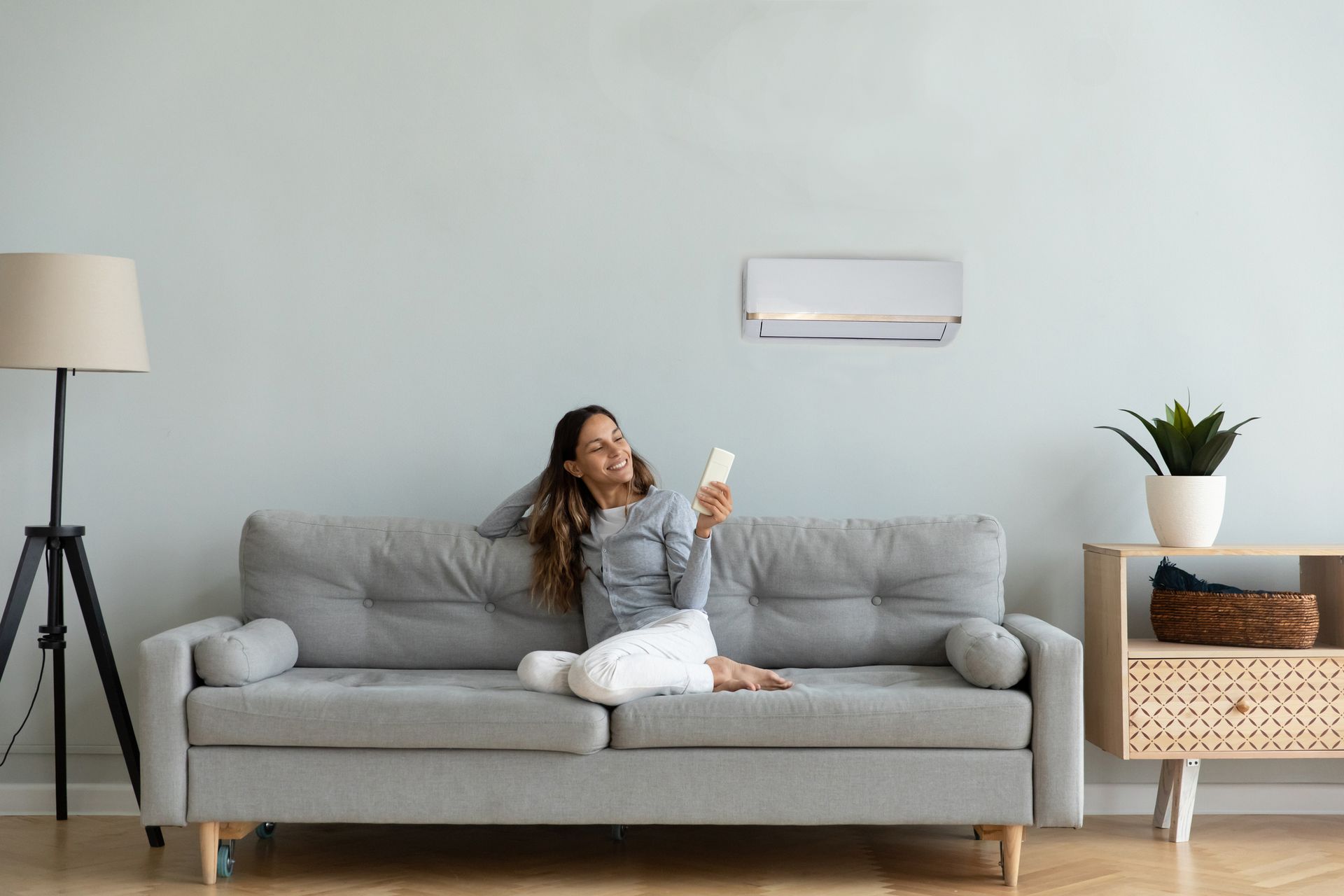 a woman is sitting on a couch in a living room holding a remote control .