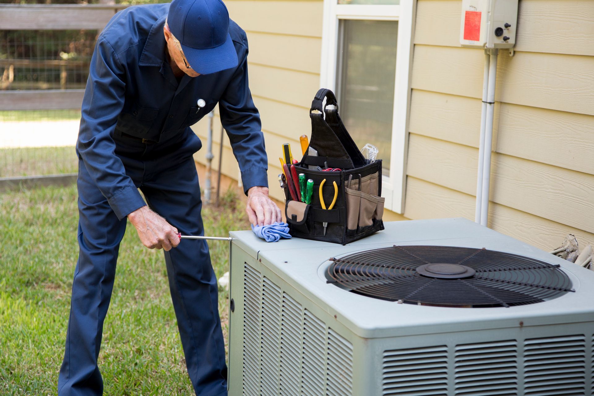 Astoria technician inspecting an air conditioning unit for repairs.