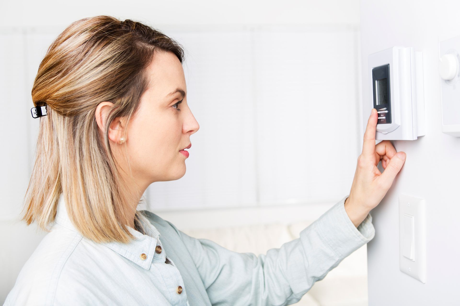 Homeowner adjusting thermostat while preparing for AC tune-up in Longwood Florida home.