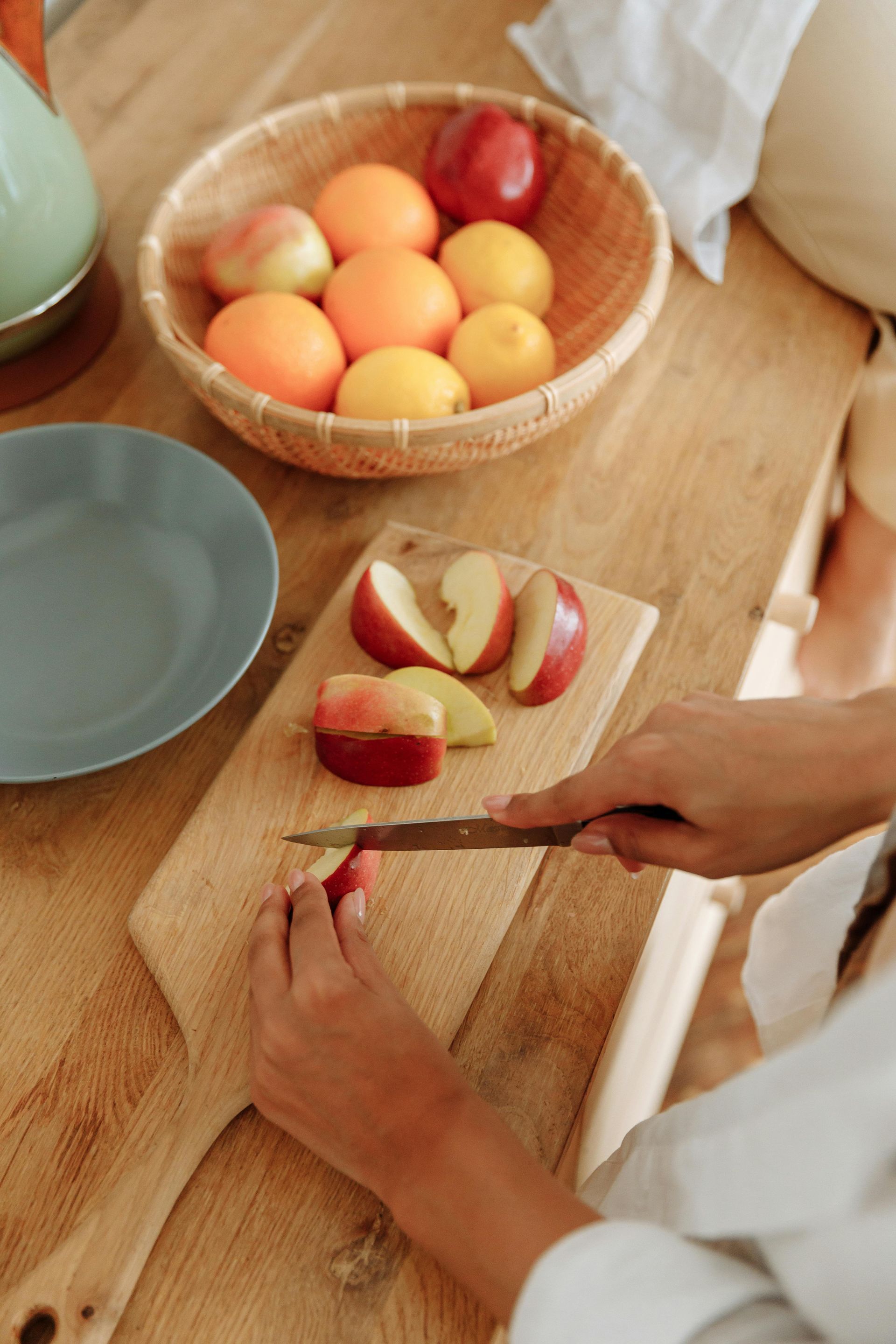 A person is cutting apples on a wooden cutting board.