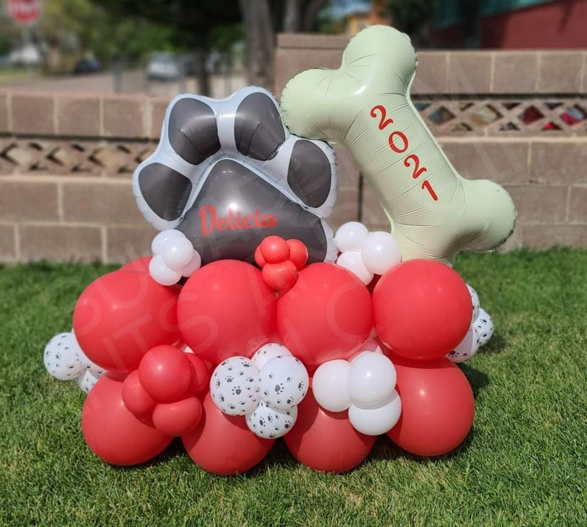 Balloon paw print display in red, white, and gray with “2021” on a bone-shaped balloon outdoors