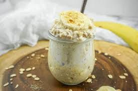Banana overnight oats in a glass jar, topped with banana slices, on a wooden board.