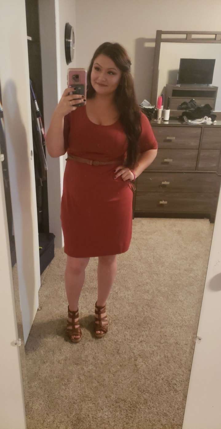 Woman in red dress and heels takes a mirror selfie.