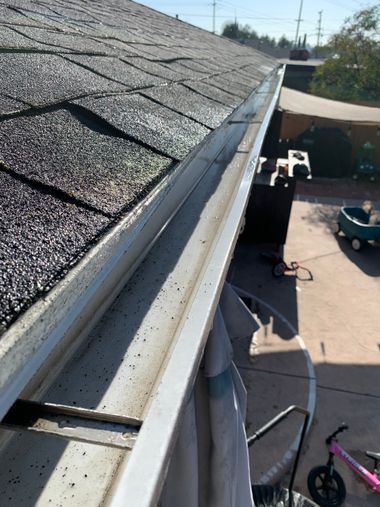 Roof edge and gutter line above a parking area, with a pink bicycle visible below.