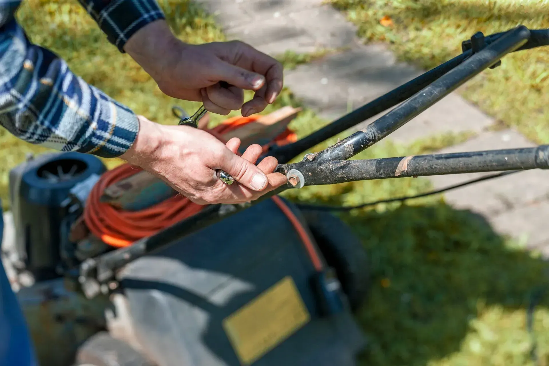 a man is fixing a lawn mower with a wrench
