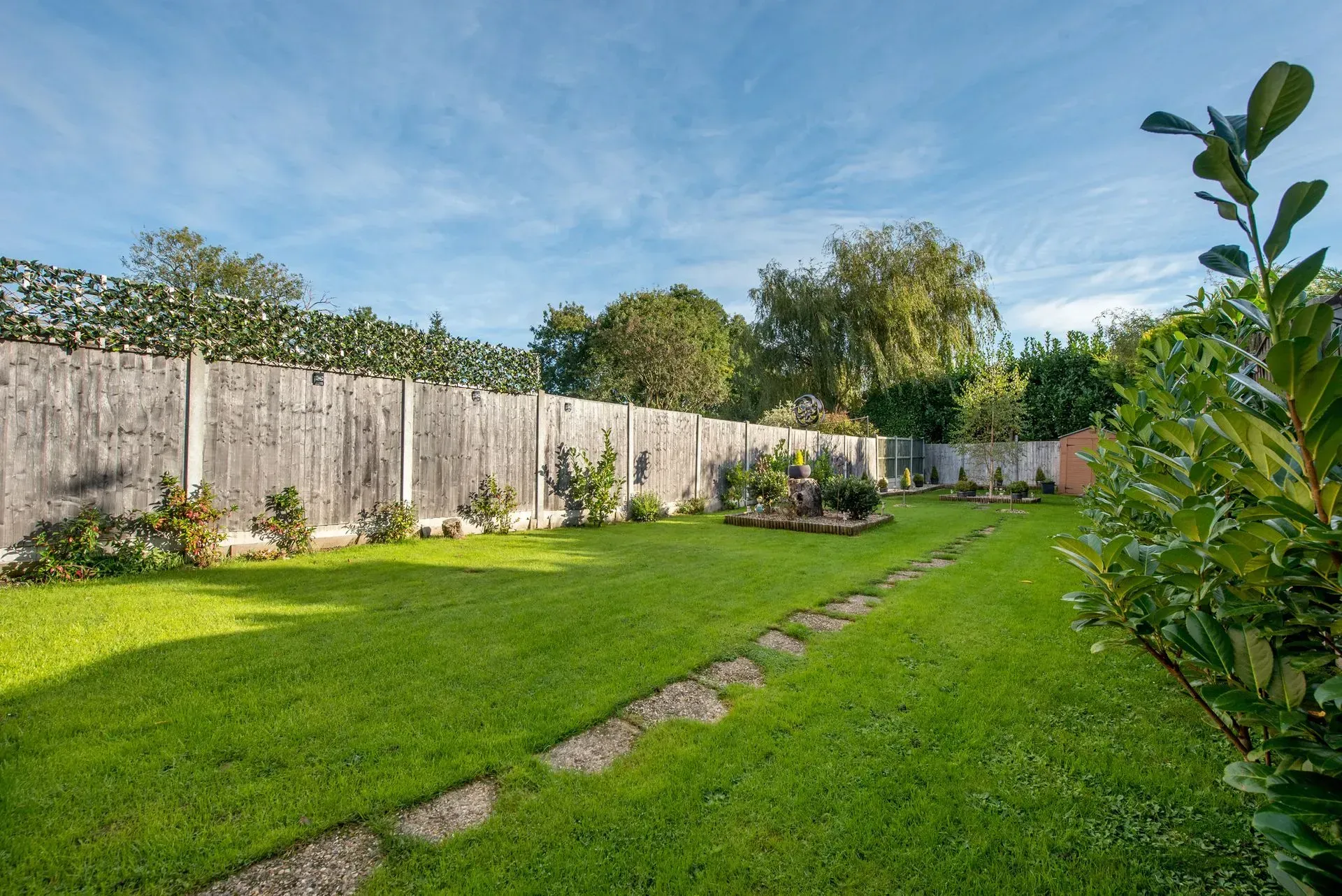 a lush green yard with a wooden fence and a path