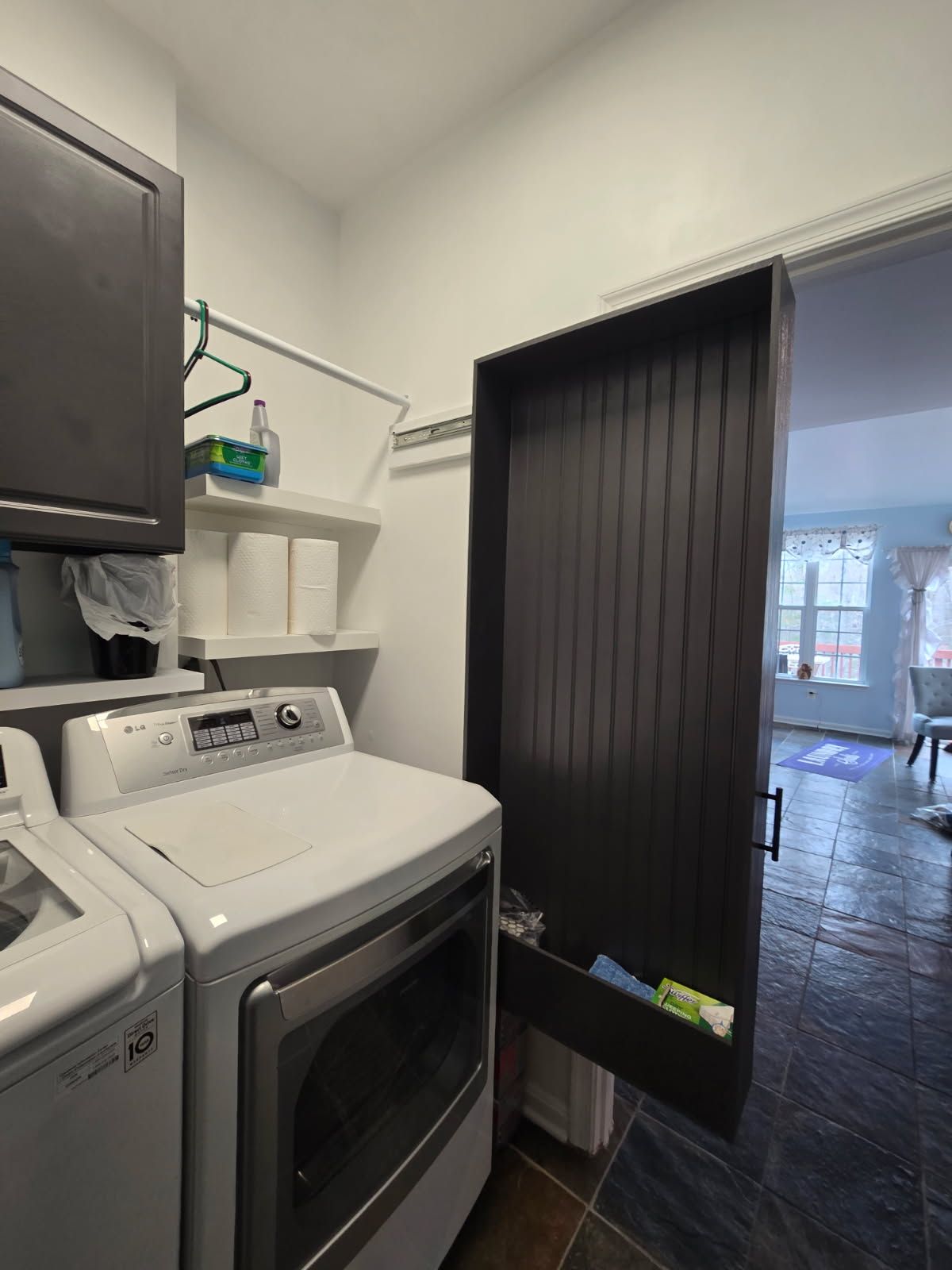 Laundry room with washer and dryer beside a doorway with a black slatted curtain.