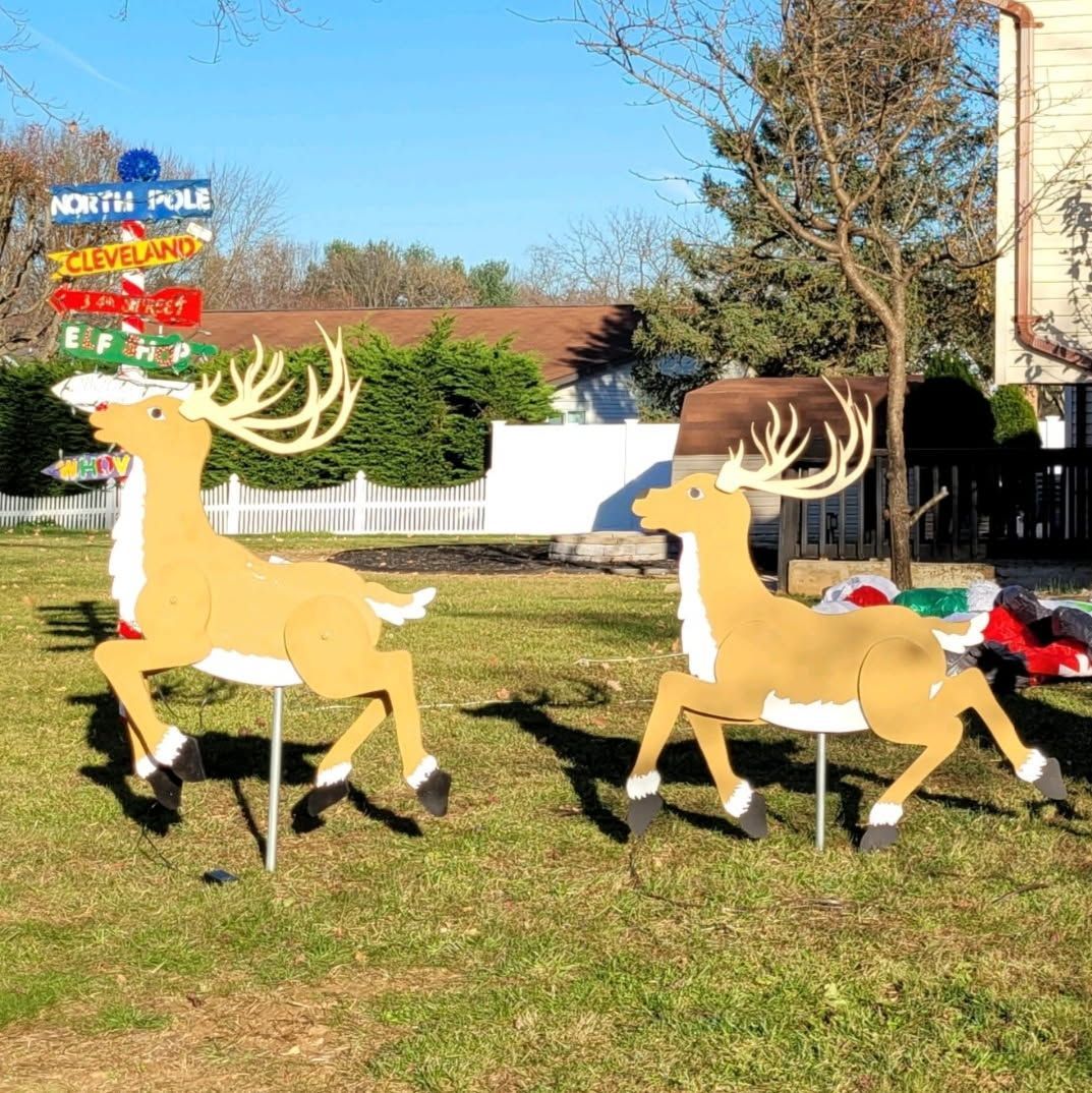 Two illuminated reindeer lawn decorations on grass in a sunny yard