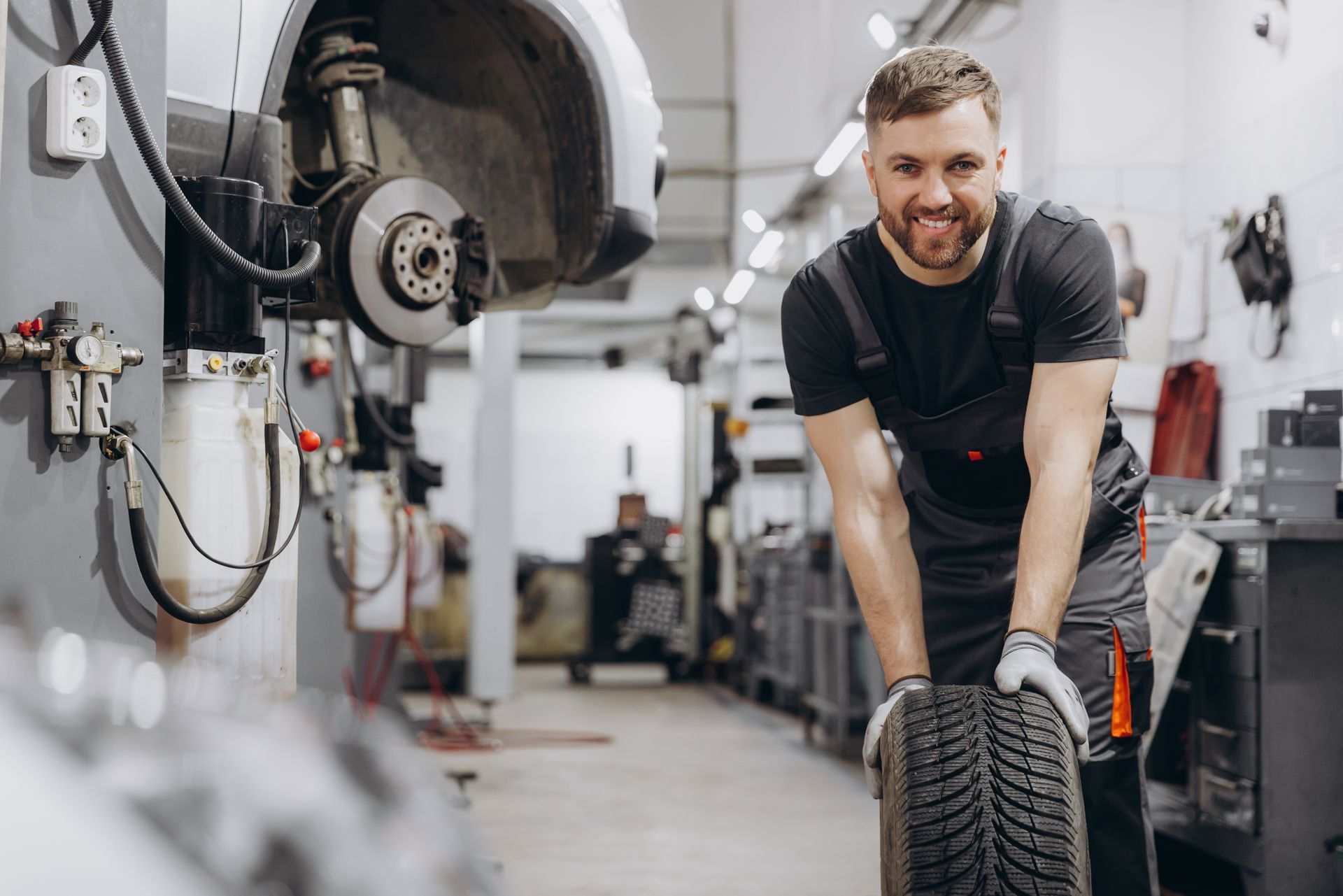 Mechanic smiling and holding a tire in an auto repair shop