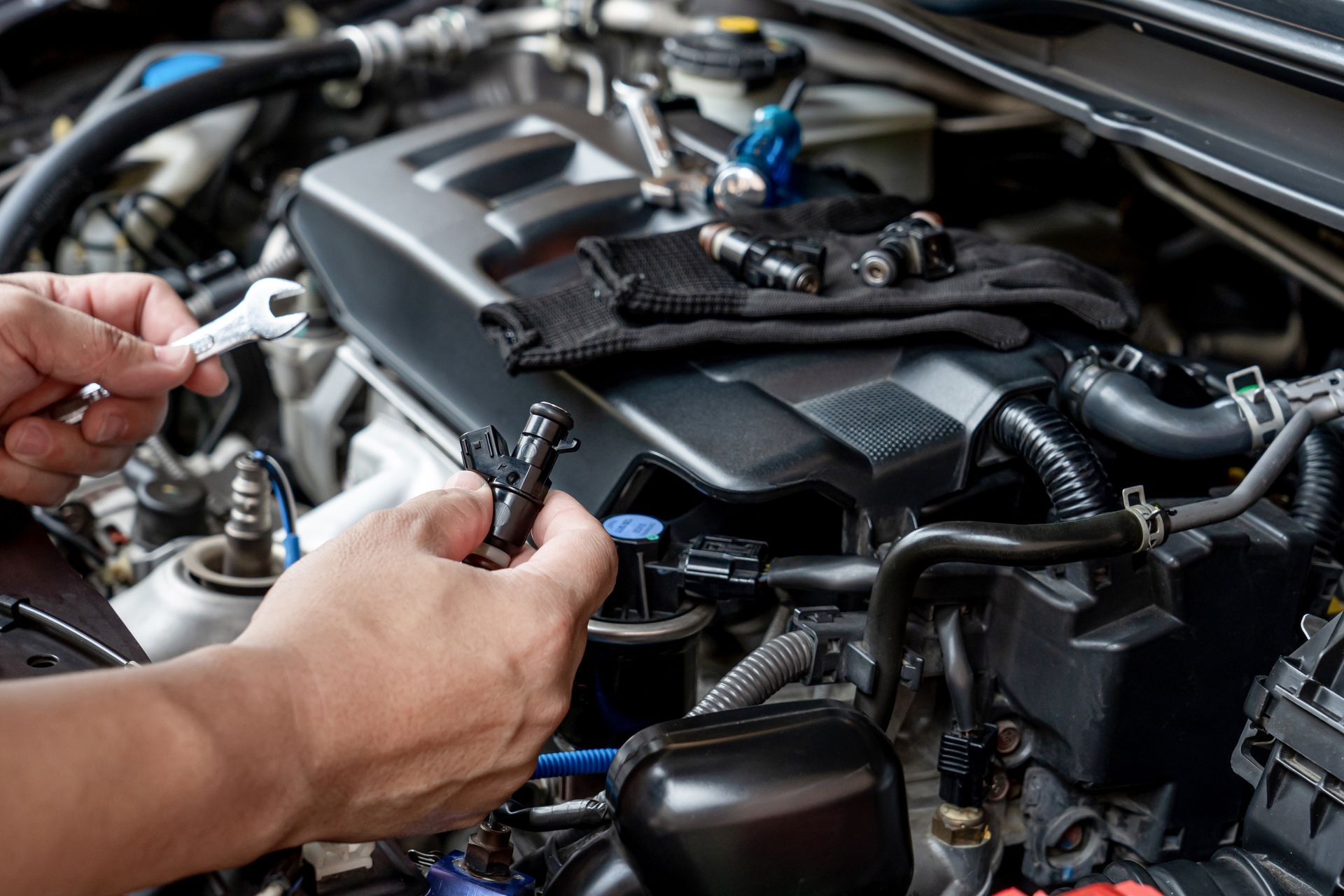 Mechanic hands installing a car engine sensor in an open hood bay Mechanic hands installing a car engine sensor in an open hood bay