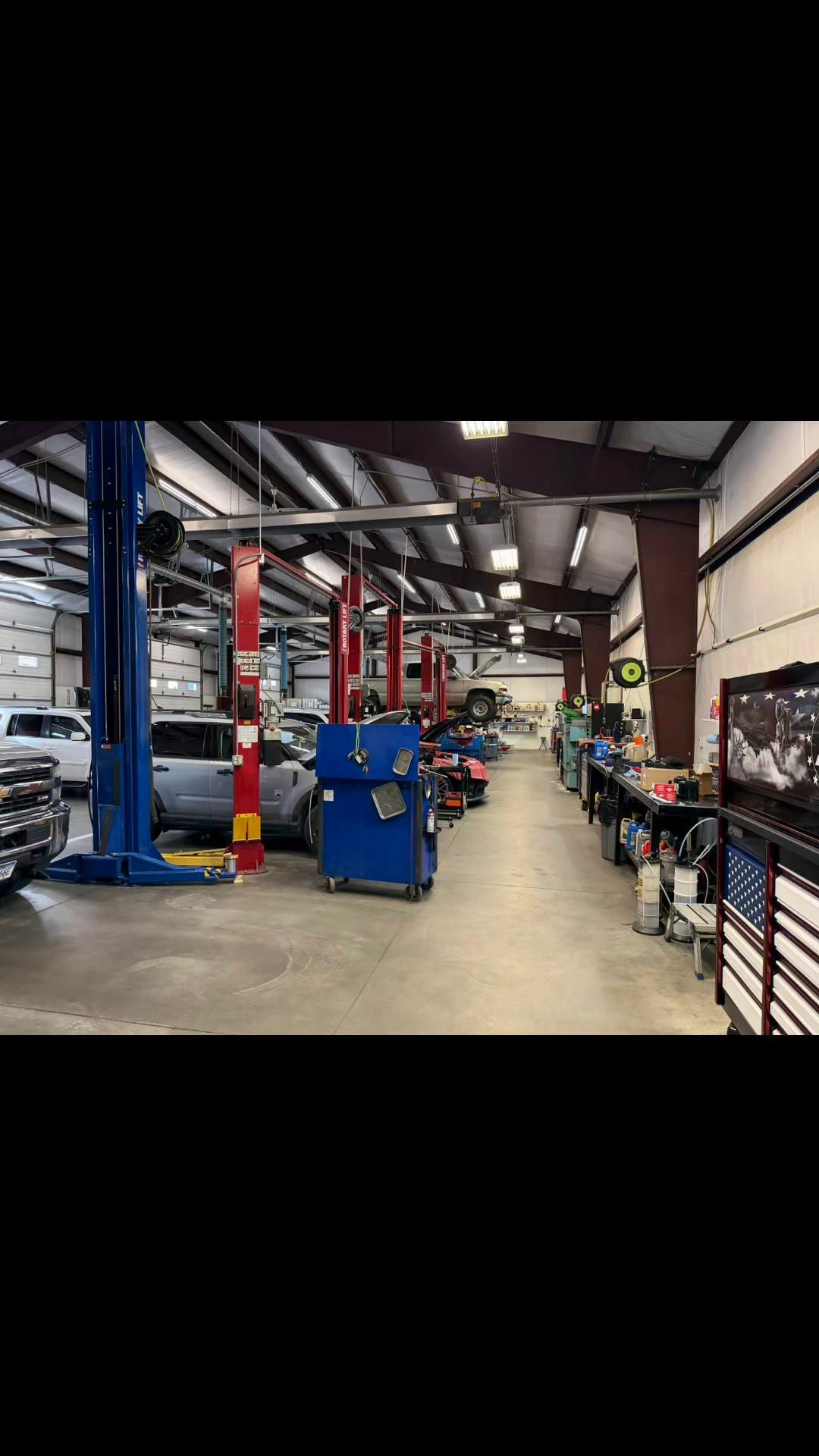 Mechanic working on a car on a lift in a modern auto repair shop, with a white SUV in the foreground Mechanic working on a car on a lift in a modern auto repair shop, with a white SUV in the foreground