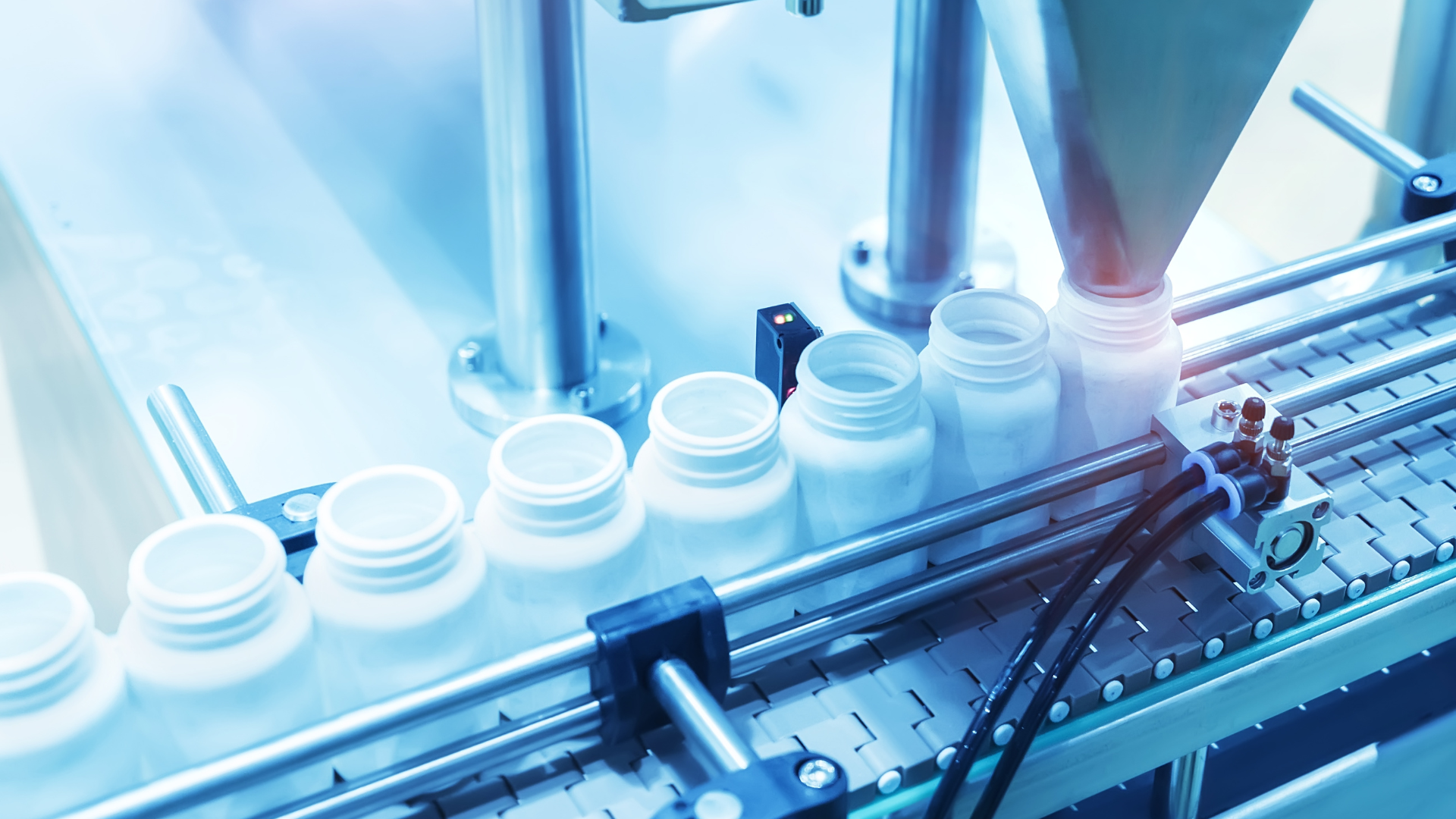 Automated bottling line filling white containers in a bright factory assembly area