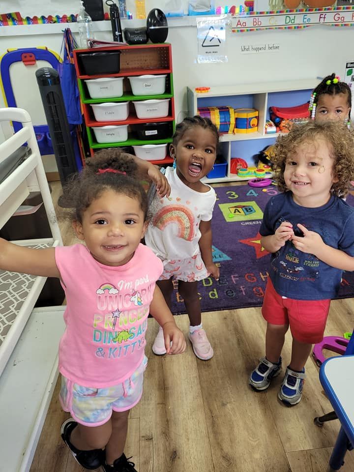 A group of young children are standing next to each other in a classroom.