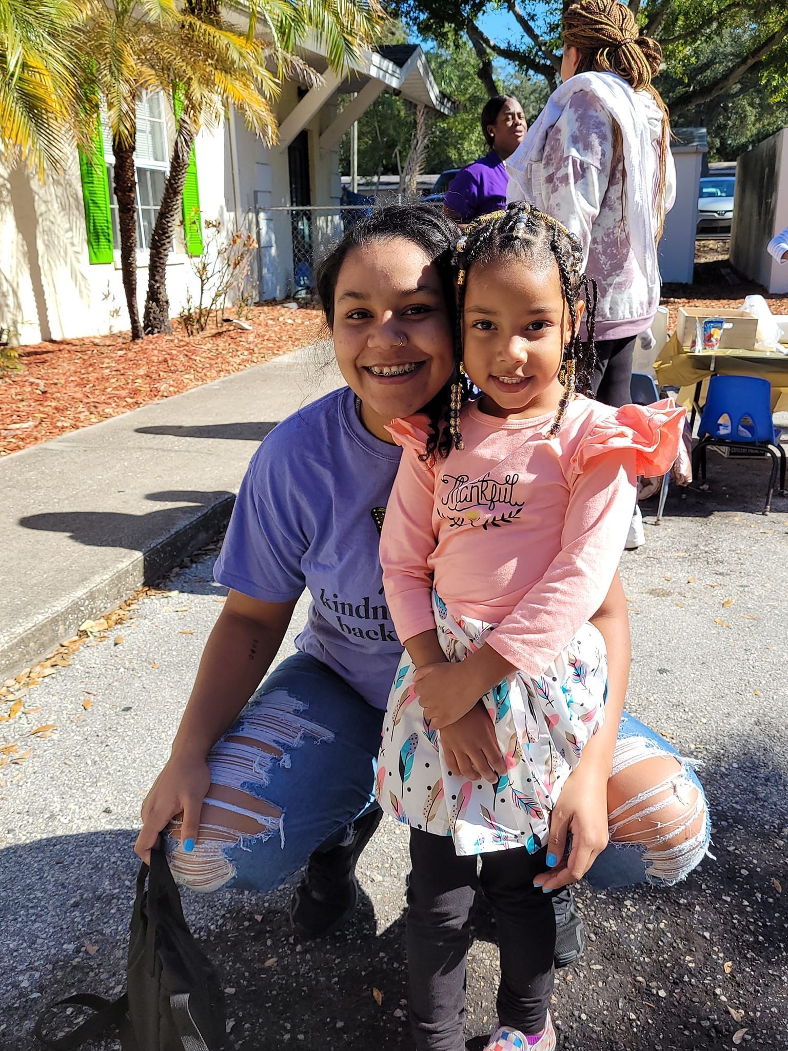 A woman is kneeling down holding a little girl in her arms.