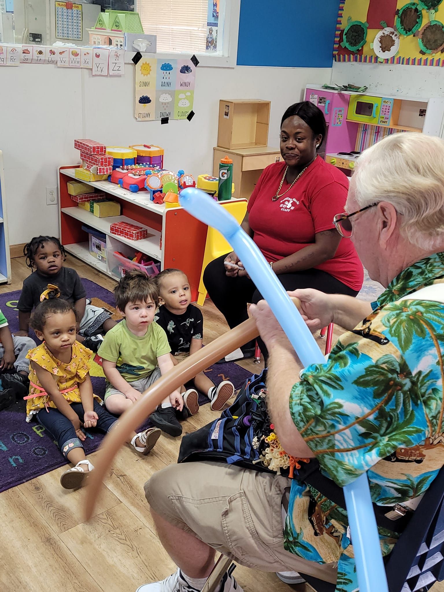 A man is holding a blue balloon in front of a group of children