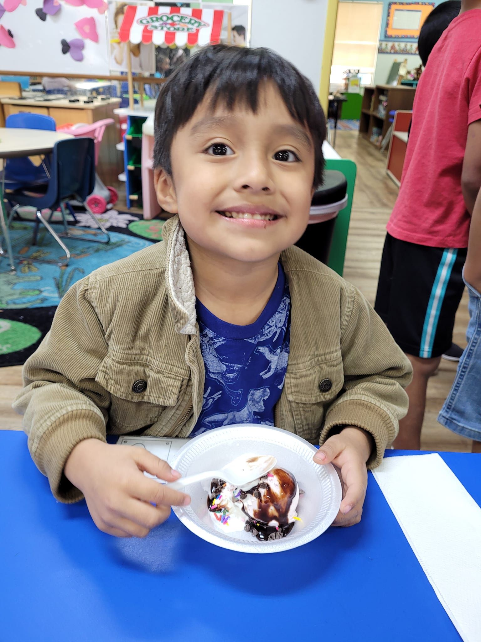 A young boy is sitting at a table with a plate of food in front of him