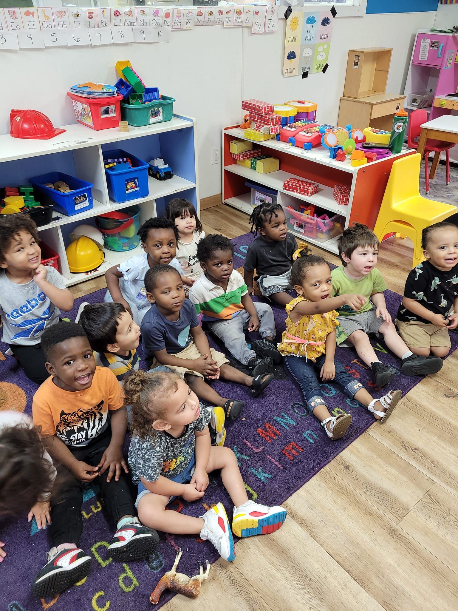 A group of children are sitting on the floor in a classroom.