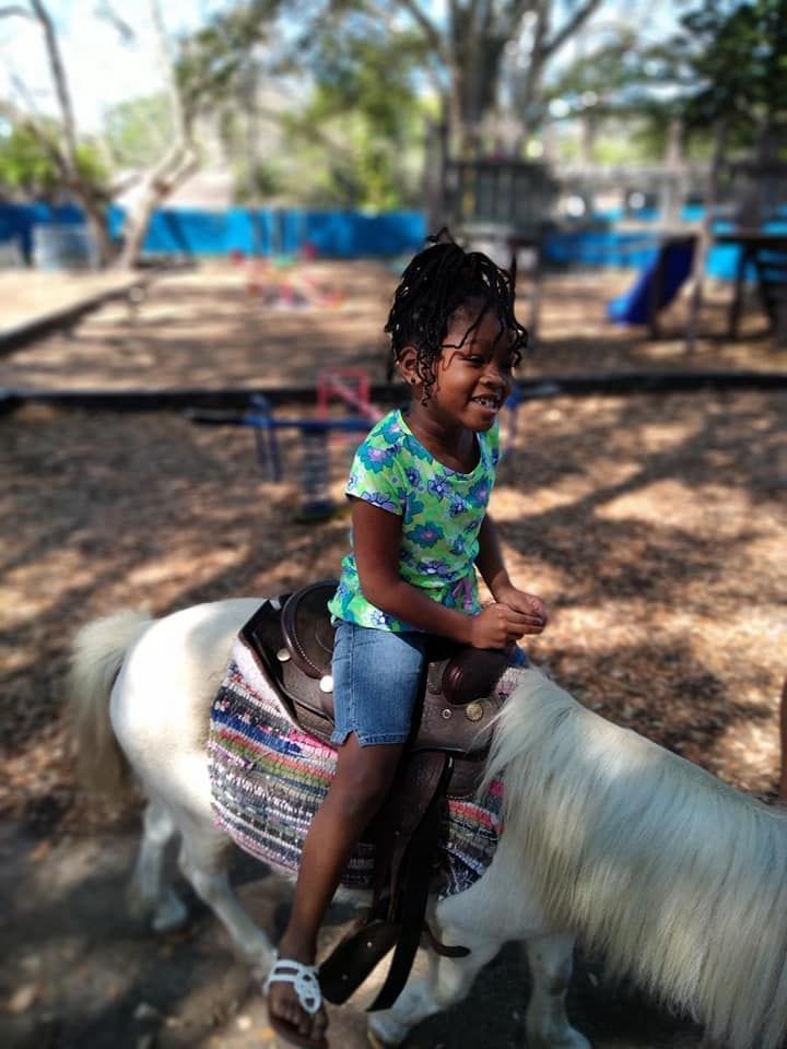 A little girl is riding a pony in a park.