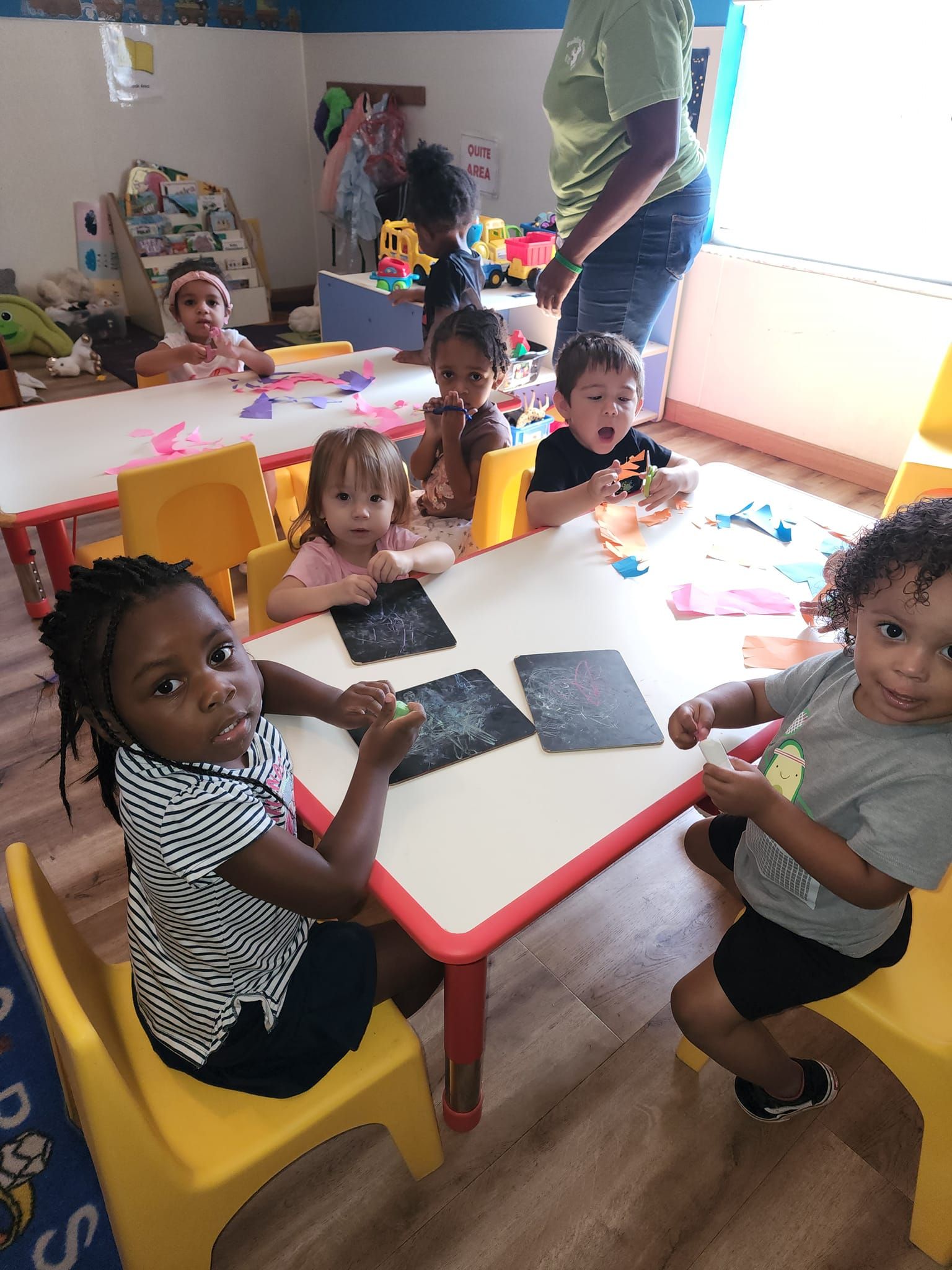 A group of children are sitting at tables in a classroom.