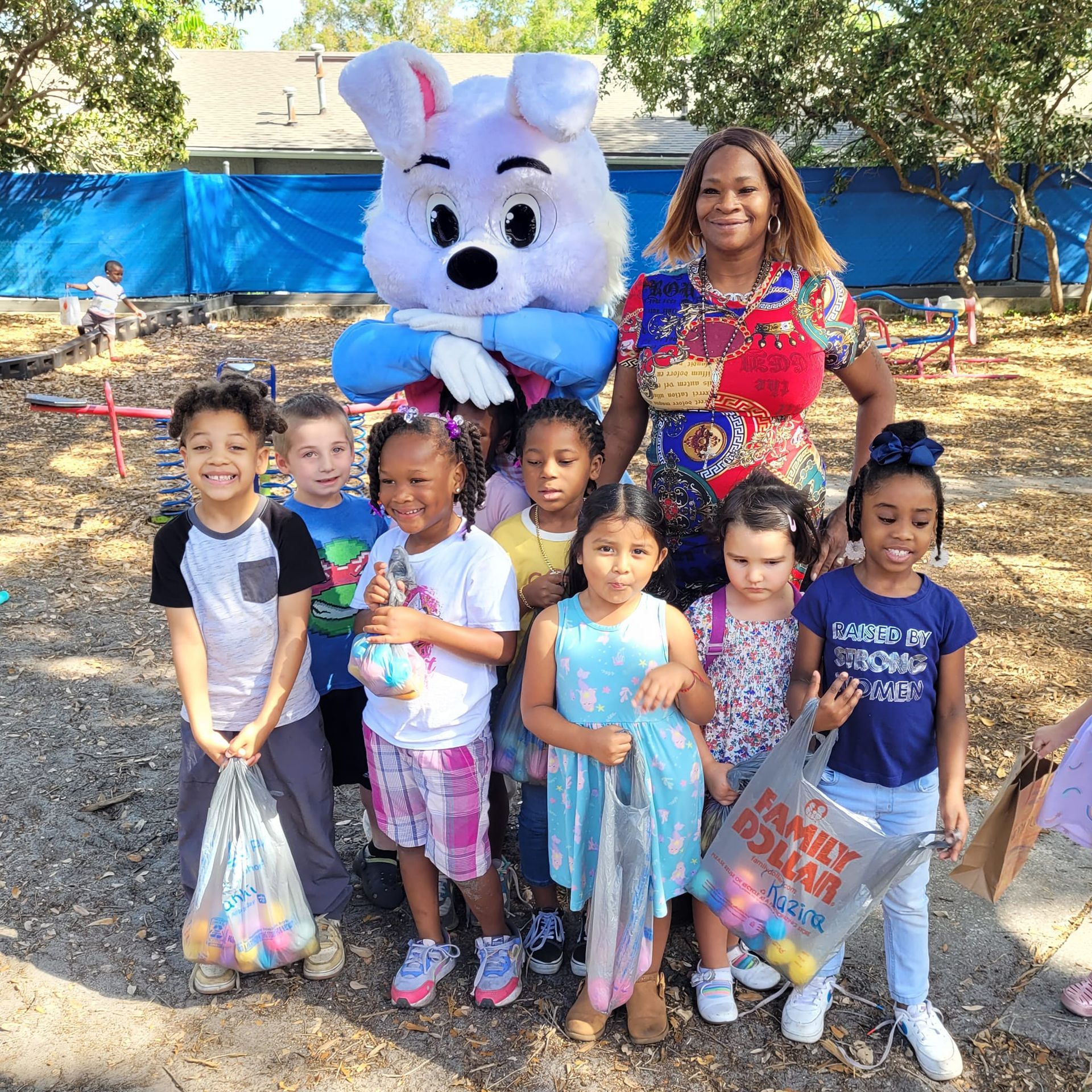 A group of children are posing for a picture with an easter bunny mascot.