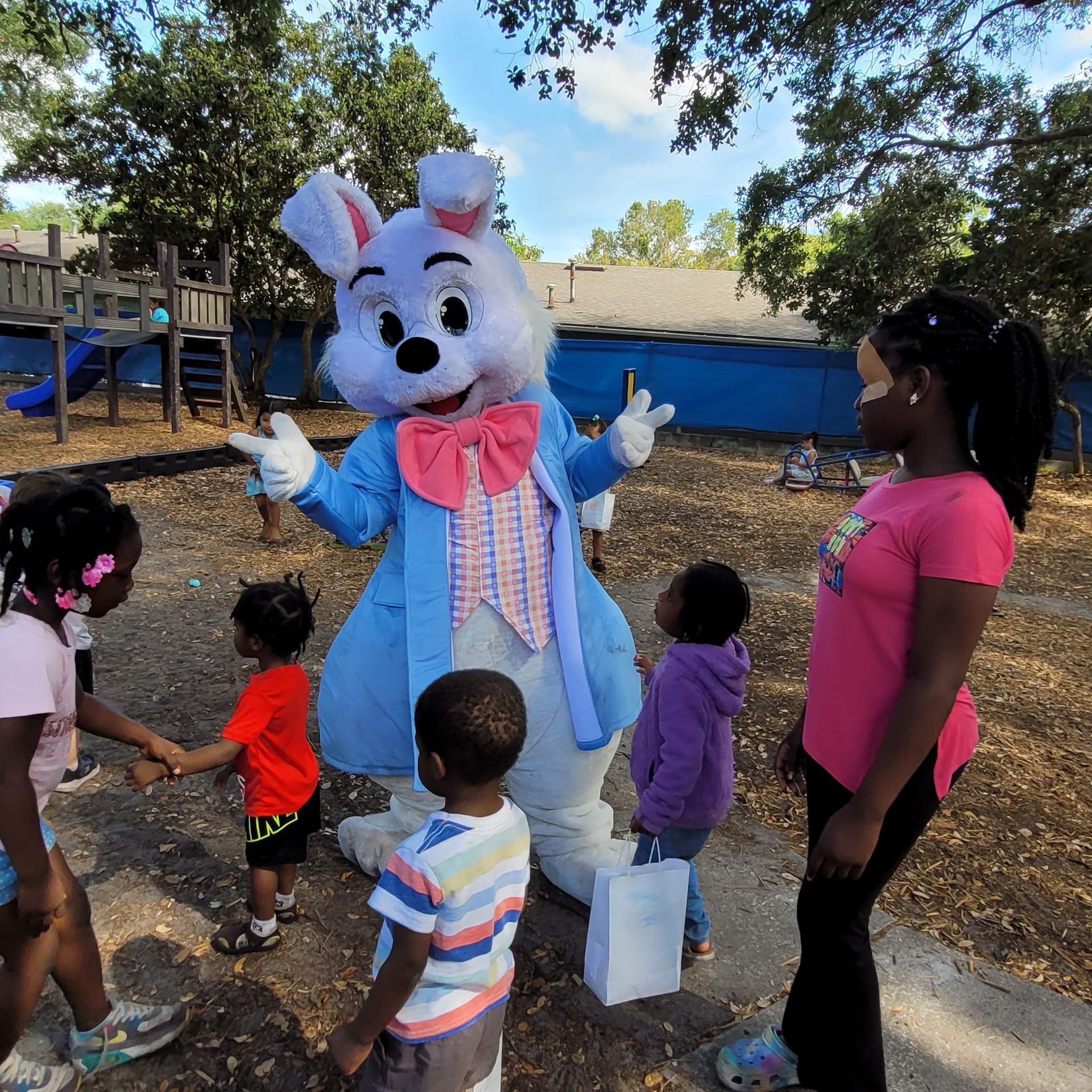 A group of children standing around a bunny mascot