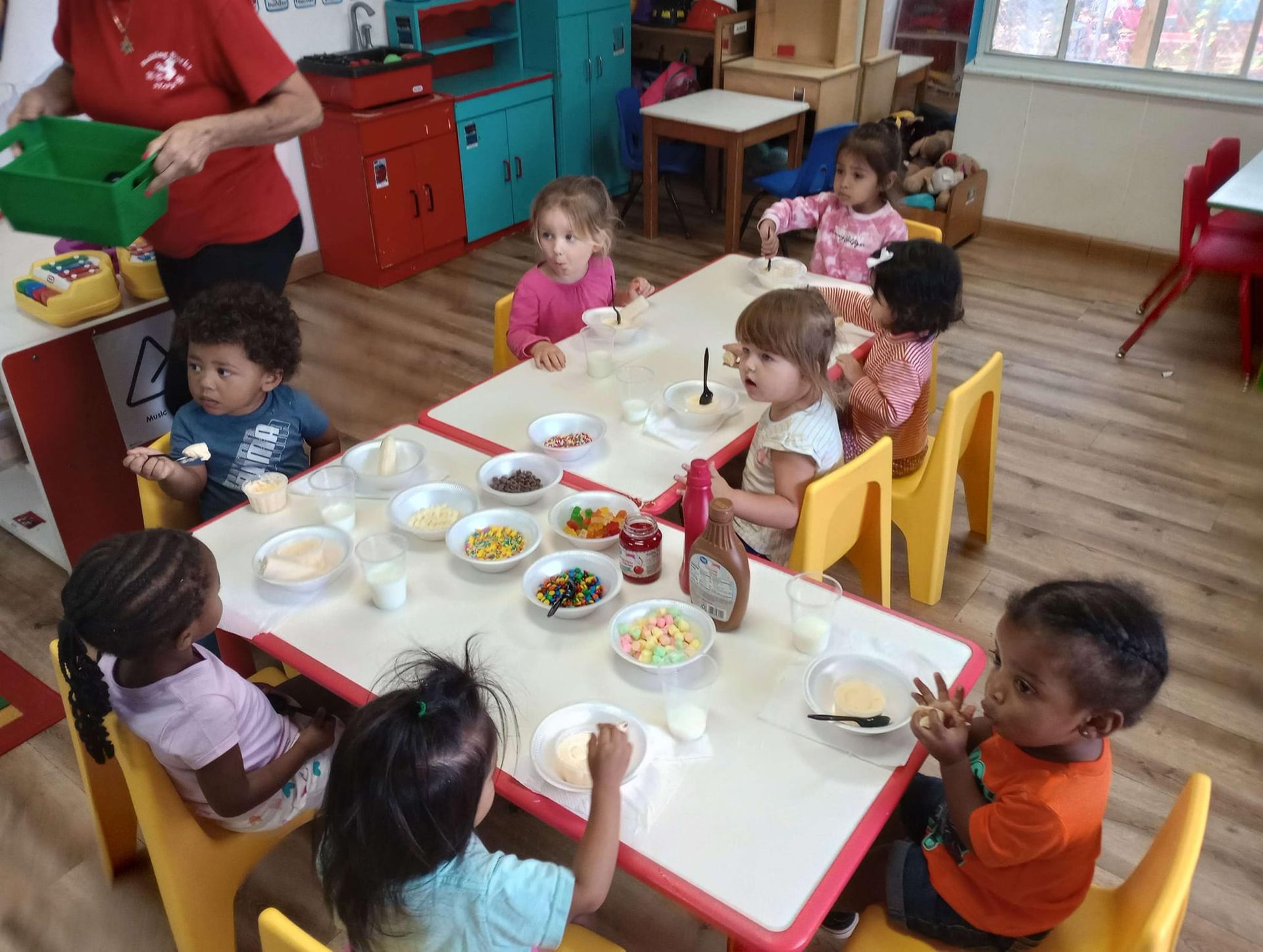 A group of children are sitting at tables eating food.