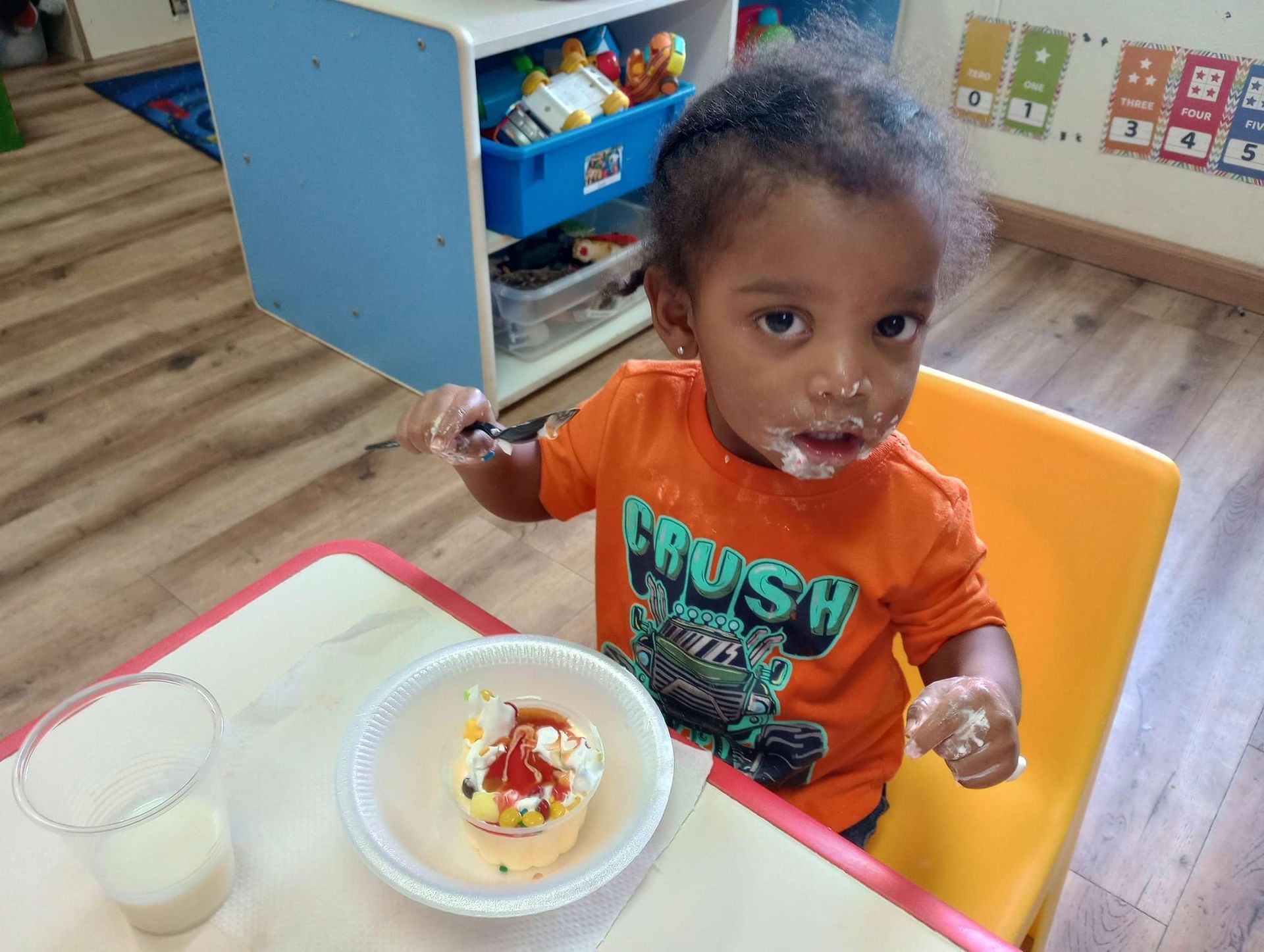 A young boy is sitting at a table with a bowl of food and a glass of milk.