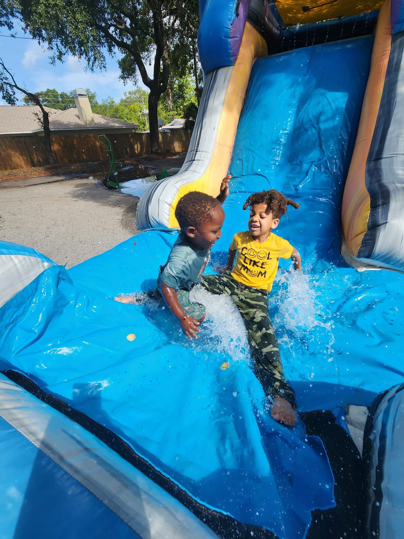 Two young boys are playing on an inflatable water slide.