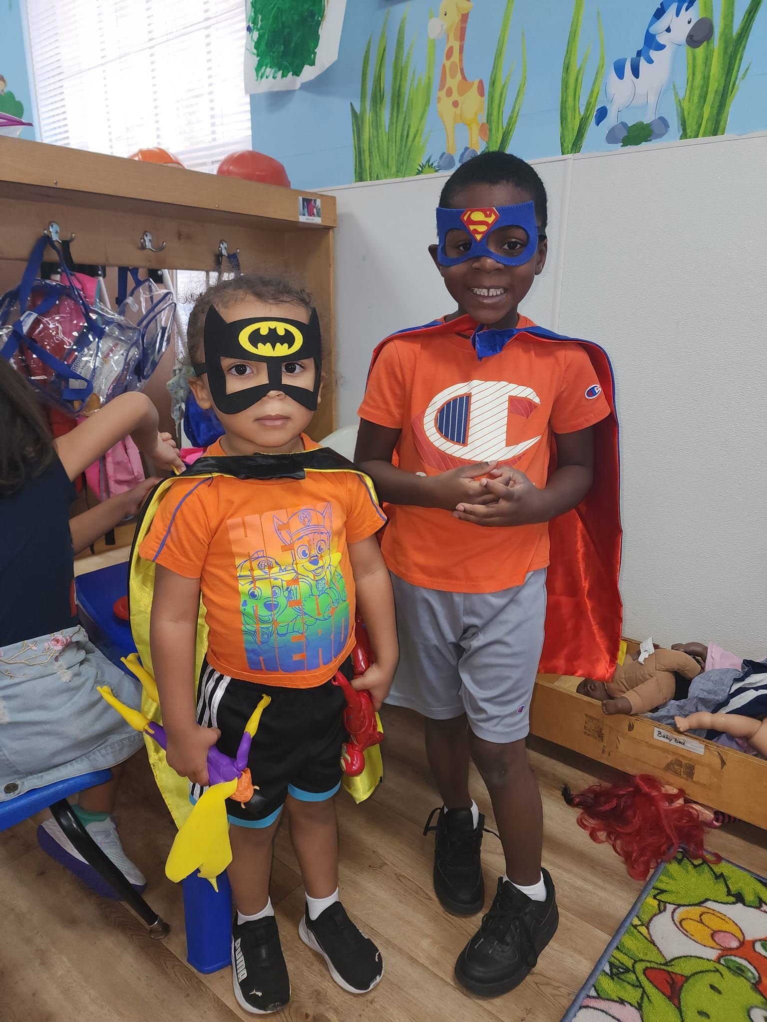 Two young boys dressed in superhero costumes are standing next to each other.